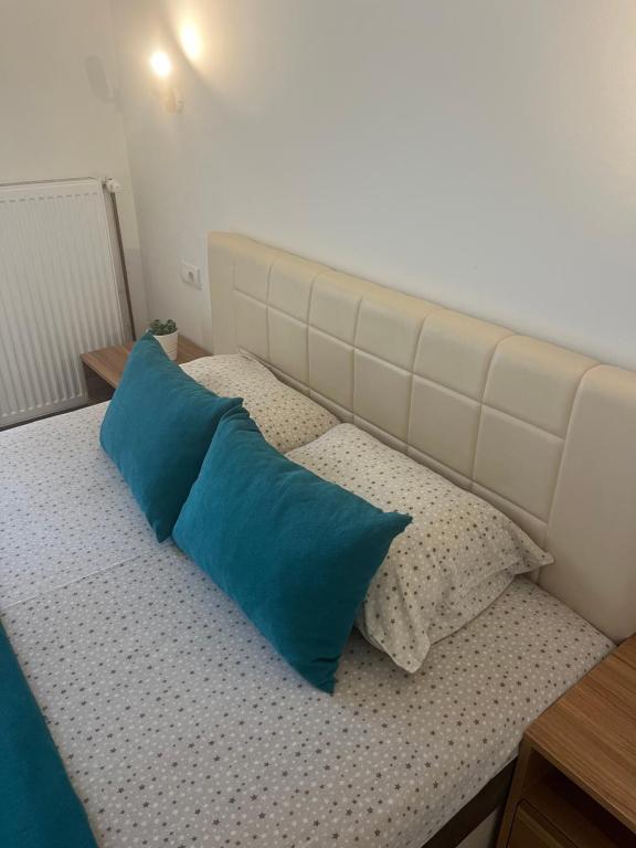 a bed with two blue pillows on it at Apartmani Tesla in Soko Banja