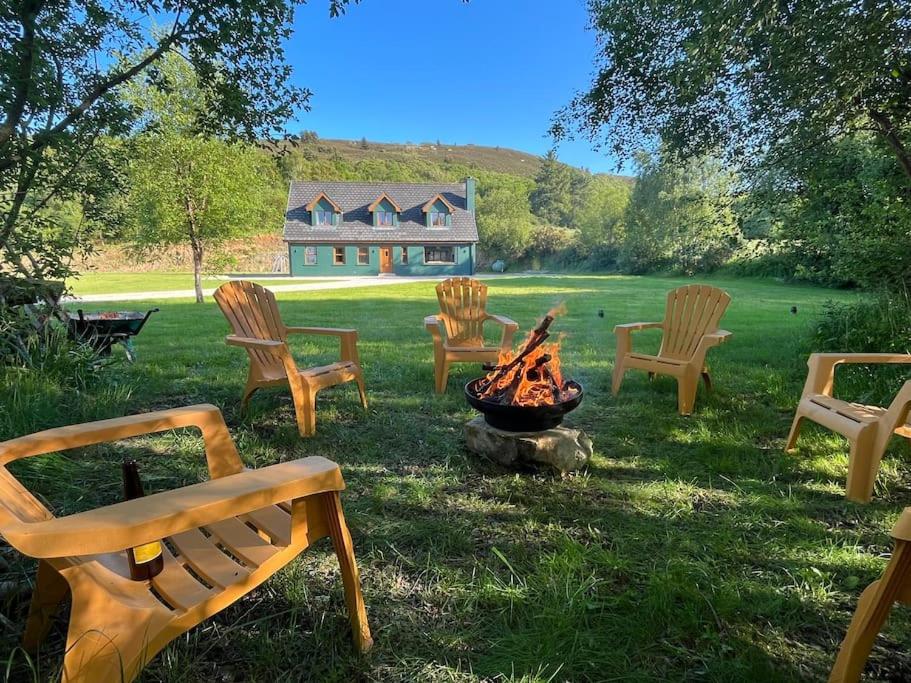 5-bed house near Rathmullan beach في راثمولان: مجموعة من الكراسي يجلسون حول النار في الفناء