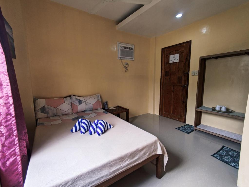 a bedroom with a bed with blue pillows on it at Francis Dale Lodge L3 in El Nido