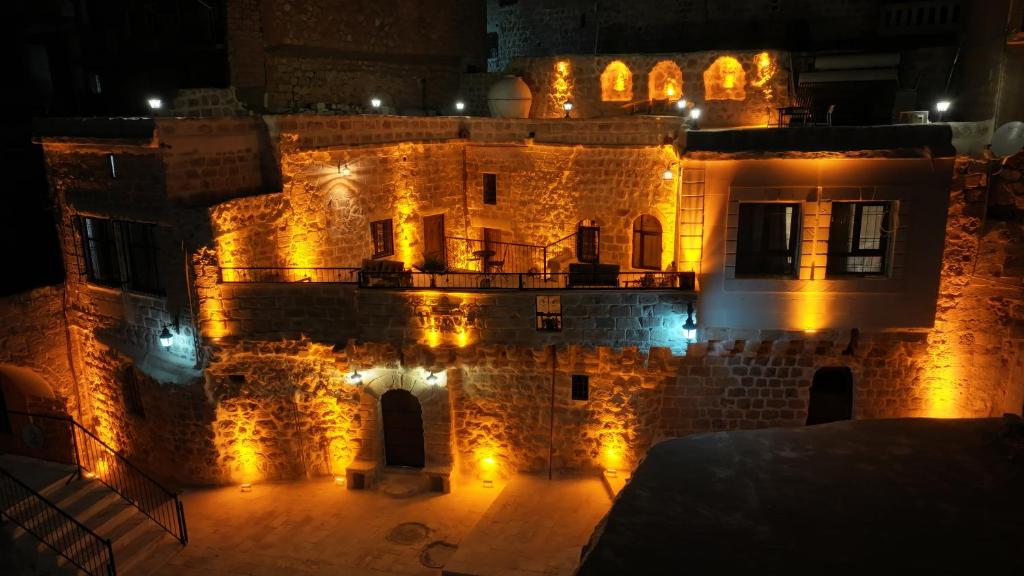 un vieux bâtiment avec des lumières la nuit dans l'établissement ŞEHRAZAD OTEL MERDİN masal şehri konağı, à Mardin