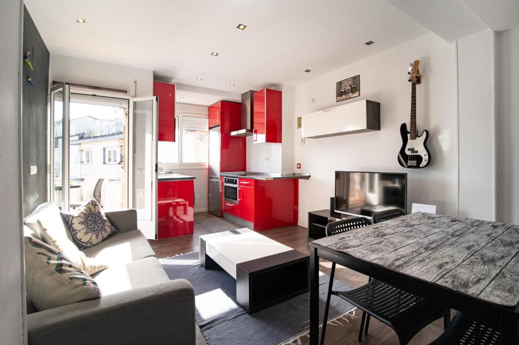 ein Wohnzimmer mit einem Tisch und eine Küche mit roten Schränken in der Unterkunft Apartment Amara AMONAREN ETXEA Free WiFi, ROOMS, rent parking in San Sebastián