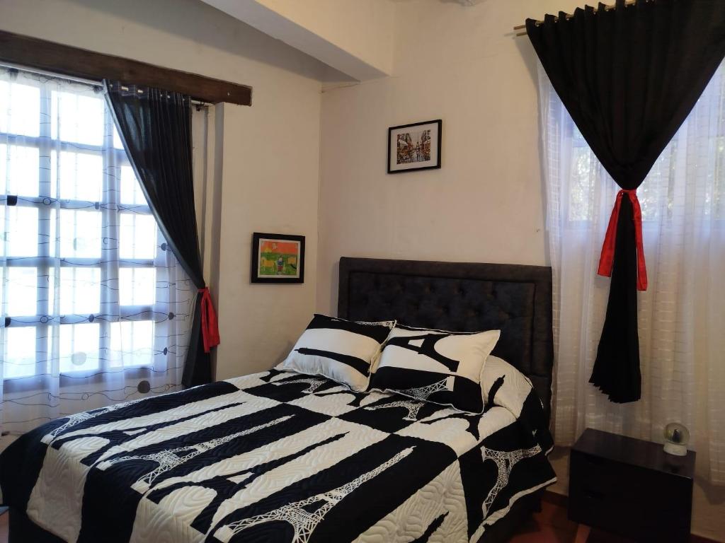 a bedroom with a black and white bed and a window at Apartamento ALTAMIRA de la VILLA de Leyva in Villa de Leyva