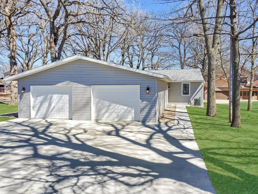a house with a garage in a yard with trees at Grassy Knoll Retreat on the Big Spirit Lake in Orleans
