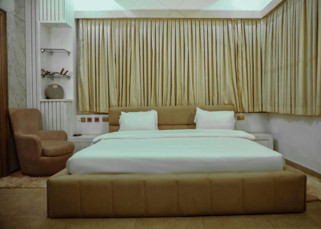 Un dormitorio con una cama grande y una silla. en Vulcan Apartments, en Mobushipe