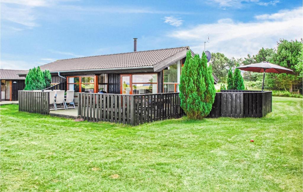 a house with a fence and an umbrella in a yard at Holiday Home Sofievej Knebel X in Skødshoved Strand