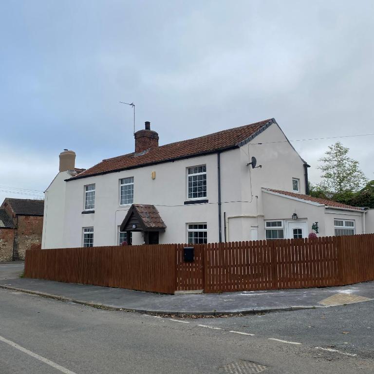 a white house with a fence in front of it at Onchan House, Beal in Knottingly