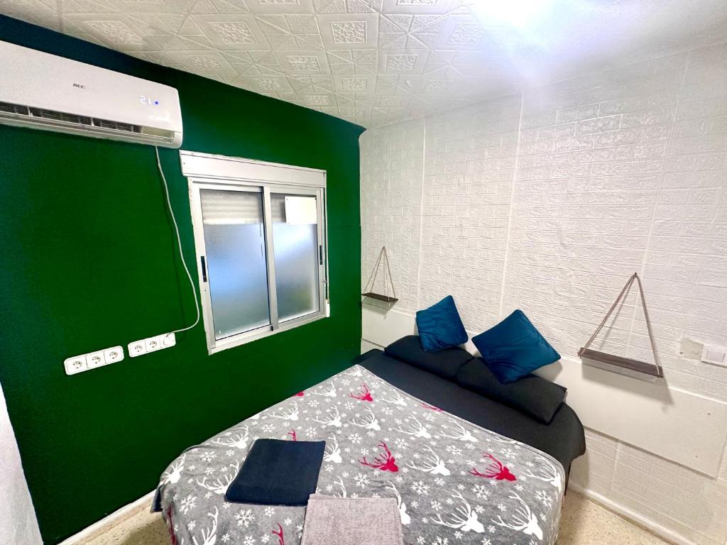 a bedroom with a green wall and a bed with blue pillows at Las habitaciones en Alicante in Alicante
