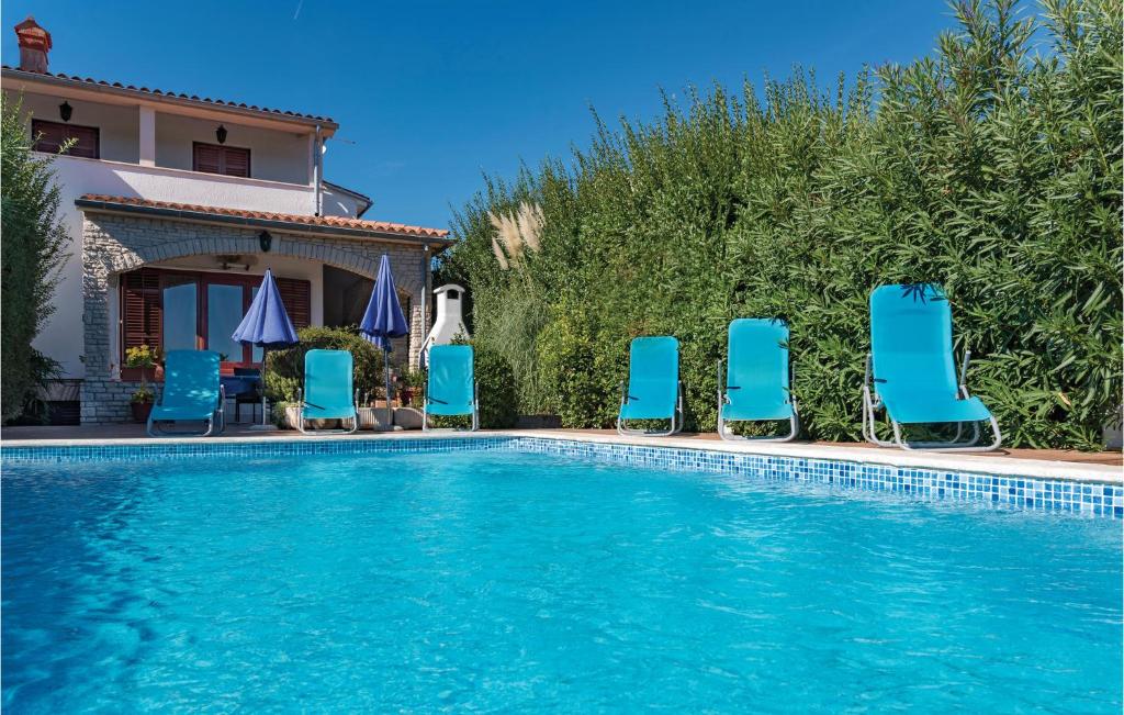 a swimming pool with blue chairs and a house at Holiday Home Krse Cr in Premantura