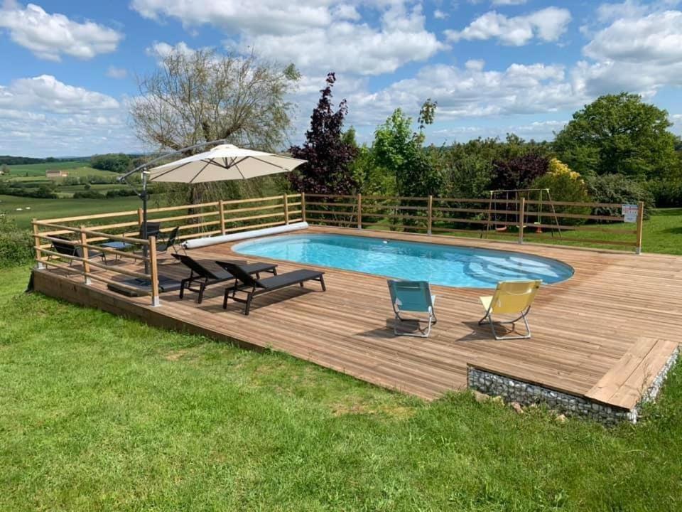 a deck with a pool and chairs and an umbrella at Tri-O-Bois in Thianges