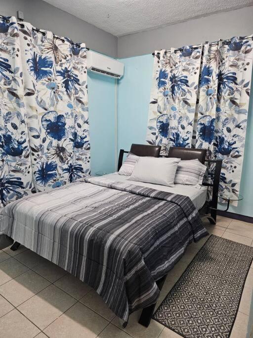 una camera da letto con un letto con tende blu e bianche di Alexander's Place a Roseau