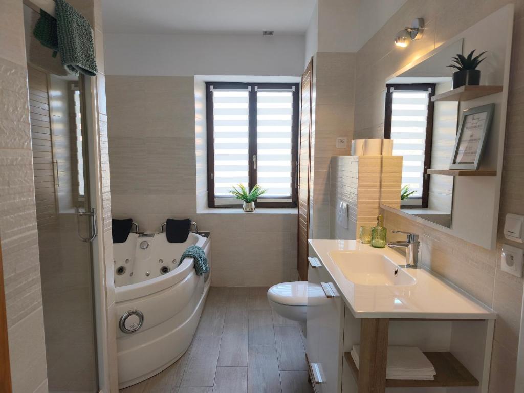 a bathroom with a tub and a toilet and a sink at Chez Aurel & Manu in Sainte-Marie-aux-Mines