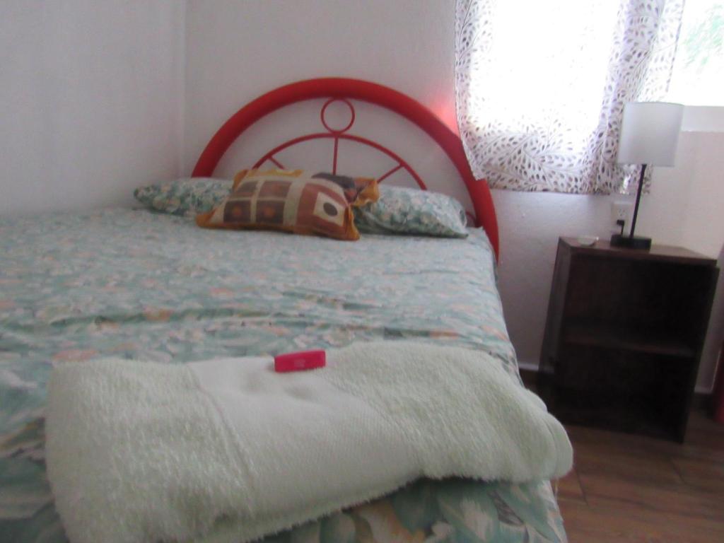 a bedroom with a bed with a red headboard at La bamba surf house in Dolores Miramar