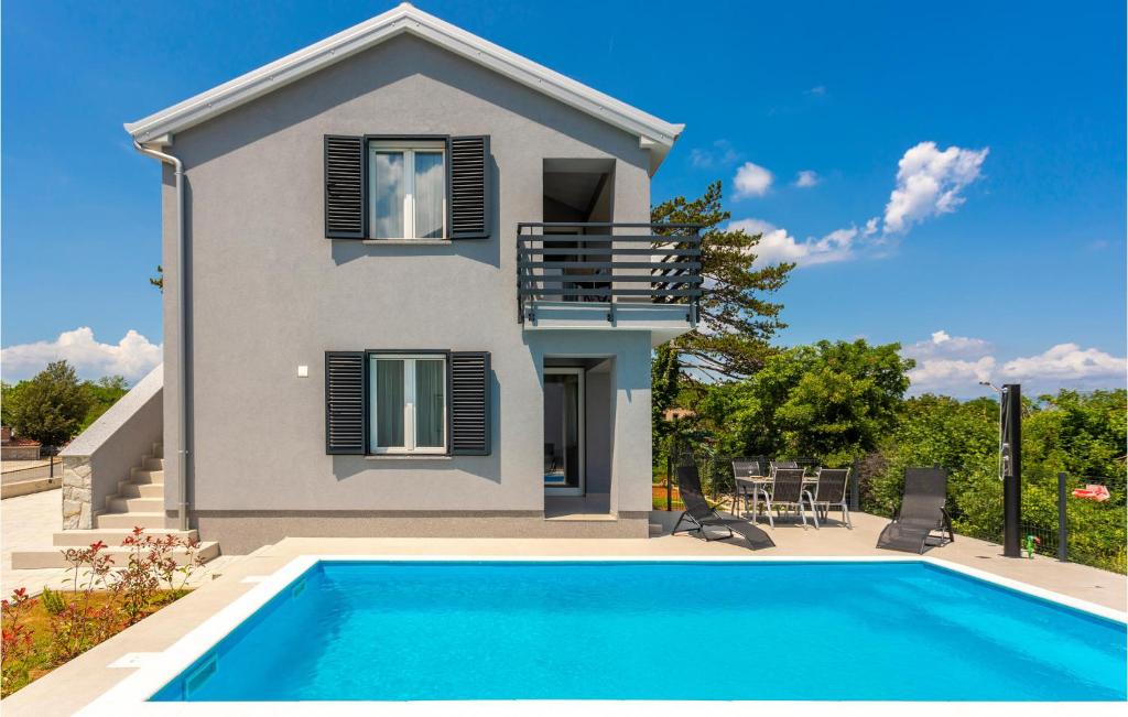 a villa with a swimming pool in front of a house at Awesome Apartment In Vrbnik With Wifi in Vrbnik