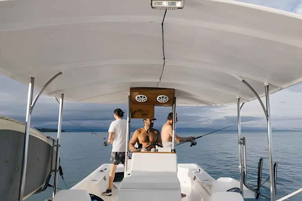 a group of three men sitting on the back of a boat at Tumbo Resort in Cabo Matapalo