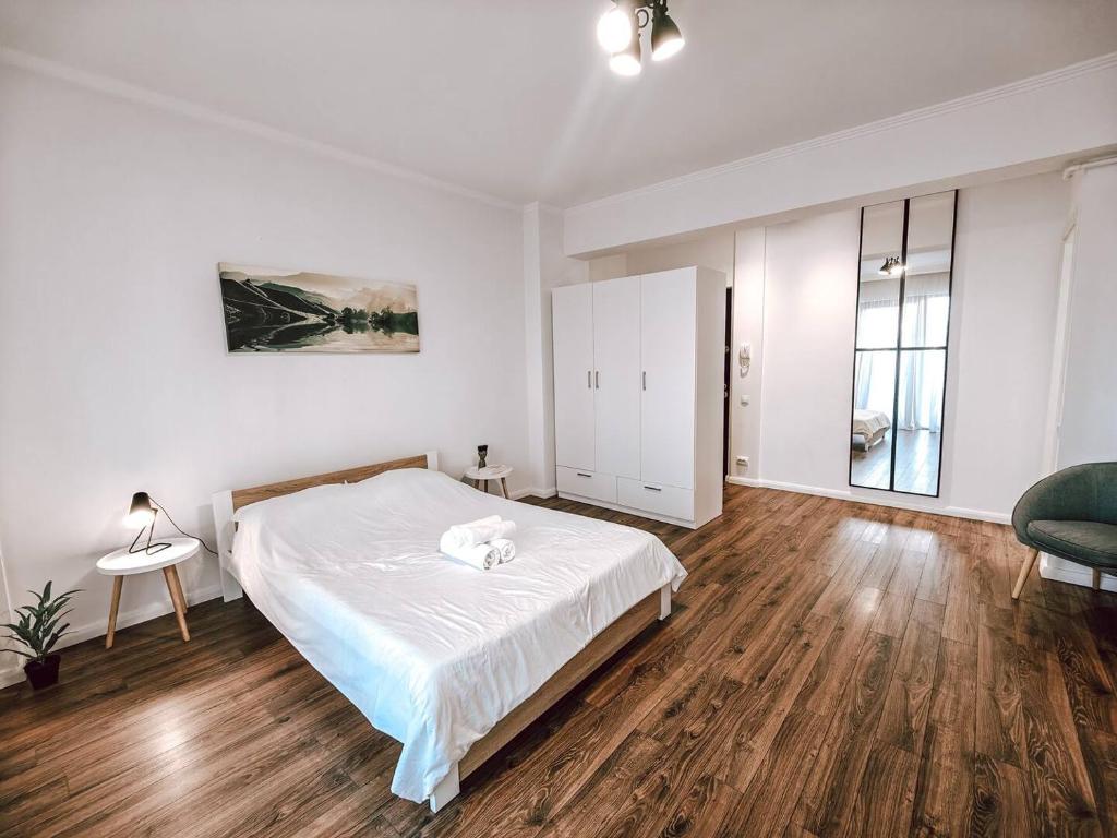 a white bedroom with a bed and a chair at Luminia Apartment in Cluj-Napoca