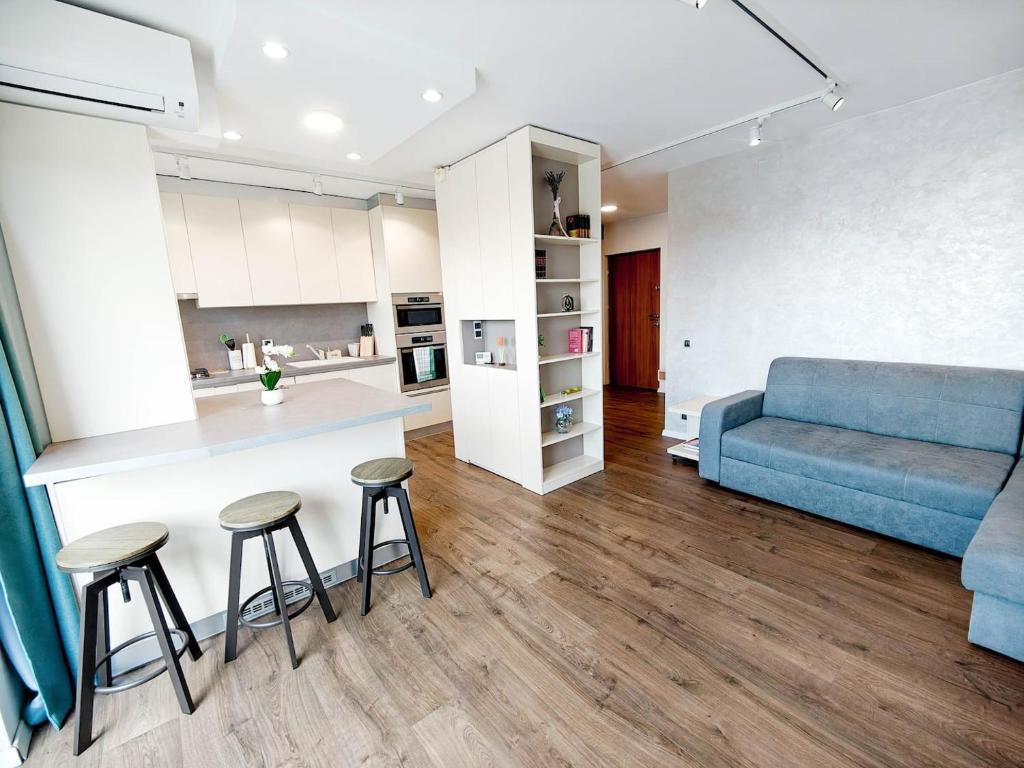 a living room with a blue couch and a table and stools at Lakeside Apartment By Iulius Mall in Cluj-Napoca