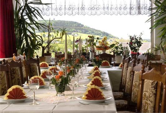 einen langen Tisch mit Weingläsern und Blumen darauf in der Unterkunft Gästehaus Hutweide in Bärenstein