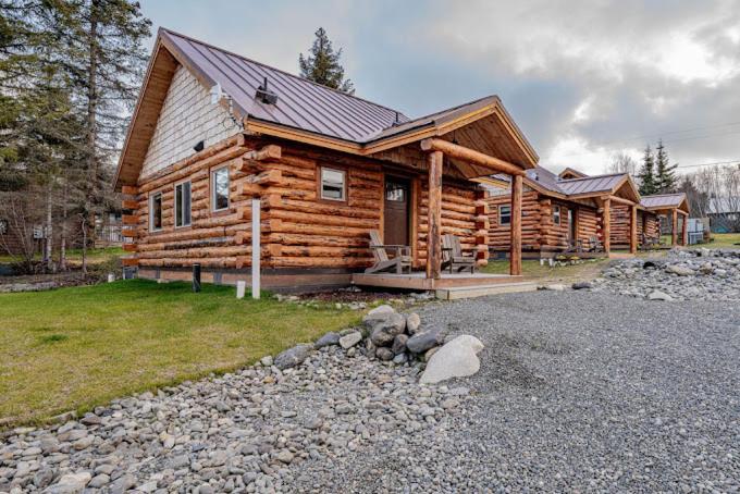 a log cabin with a pile of rocks in front of it at Lakeshore Lodging Cabins in Homer