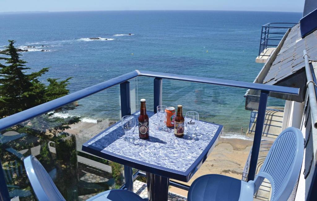 einen Tisch mit Flaschen und Gläsern auf einem Balkon mit Meerblick in der Unterkunft Amazing Apartment In Clohars-Carnoët in Clohars-Carnoët