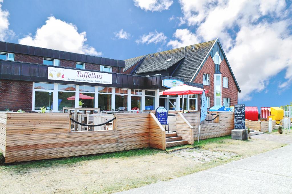 un restaurante con patio al aire libre y parque infantil en Strandhotel Achtert Diek, en Langeoog