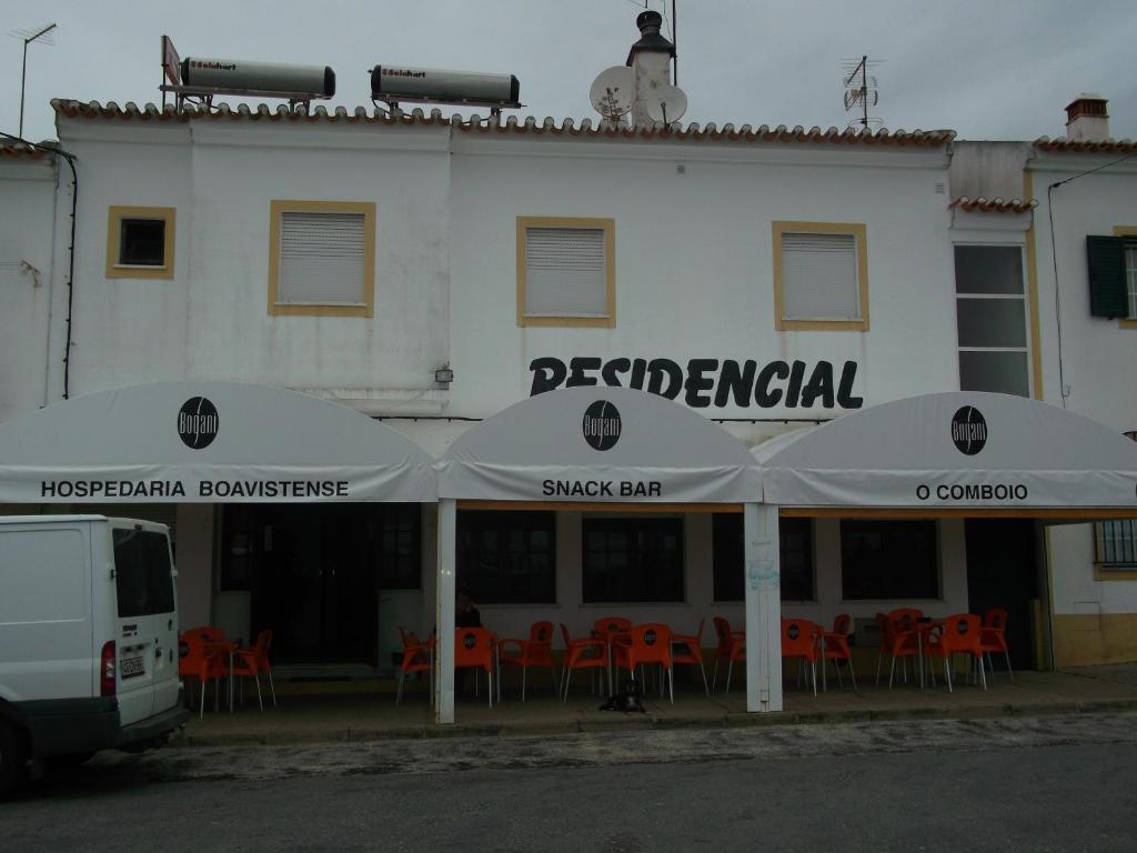 a white building with tables and umbrellas in front of it at Alojamento local Boavistense in Odemira
