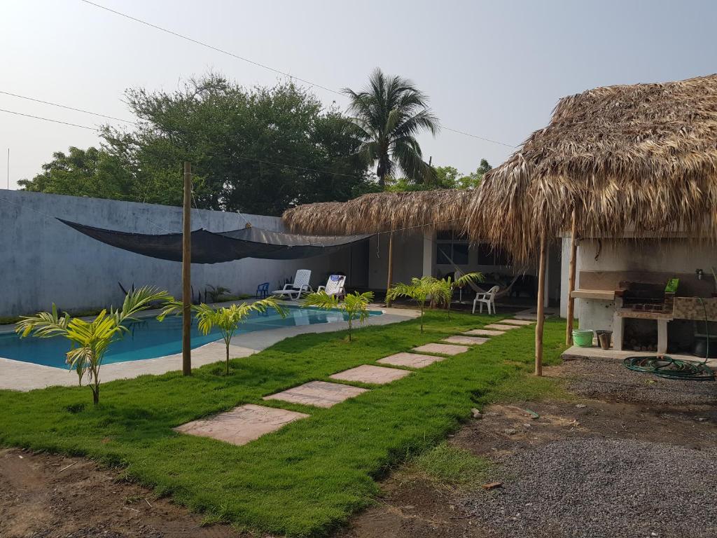un complejo con piscina y techo de paja en Casa María Victoria, en Taxisco