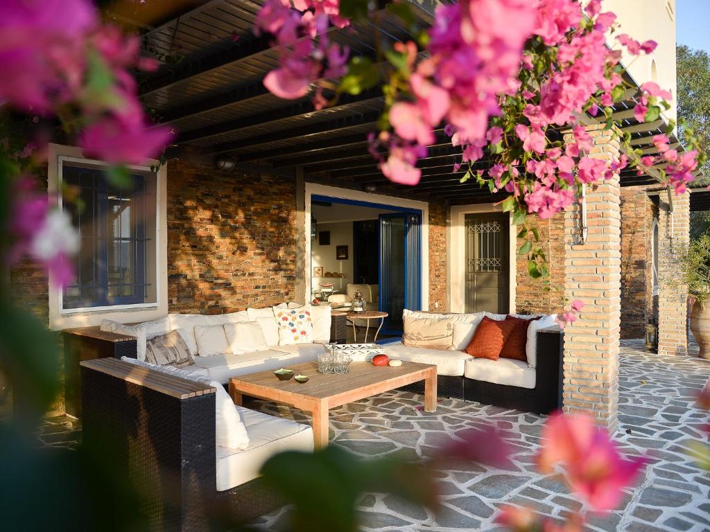 un patio con sofás, una mesa y flores rosas en Blue Fort Villas en Methoni