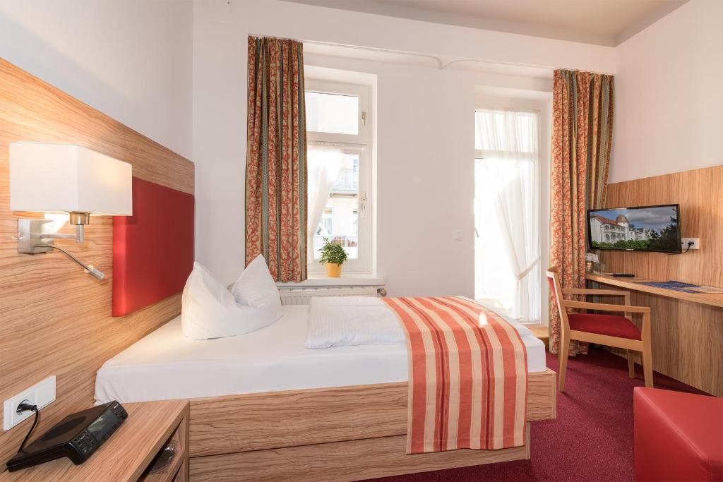 Cette chambre comprend un lit et un bureau. dans l'établissement Strandhotel zur Promenade, à Binz