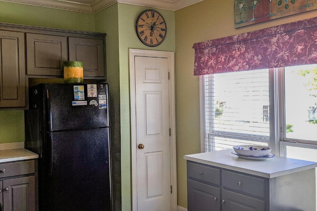 a kitchen with a black refrigerator and a clock on the wall at Sea-Side in Dauphin Island