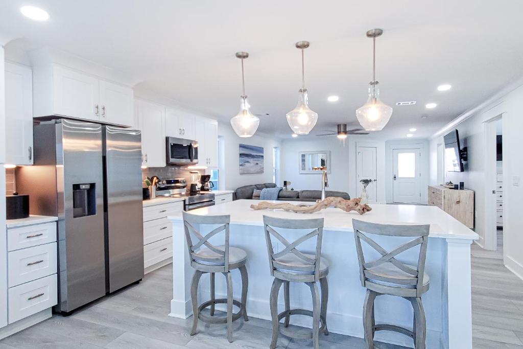 a kitchen with white cabinets and a island with bar stools at Bahia Beauty - Master House in Navarre