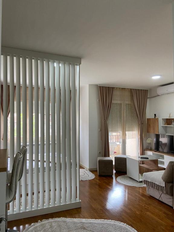 a living room with white vertical blinds on the window at River Apartman in Bijelo Polje