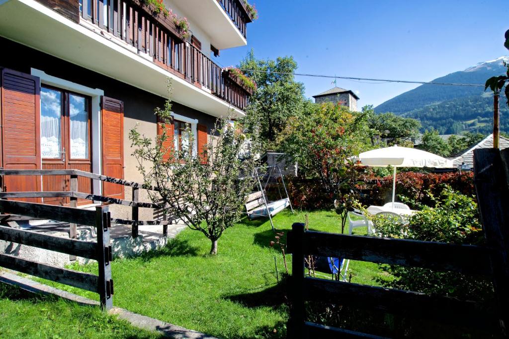 a house with a yard with a fence and an umbrella at Appartamento Reit in Bormio