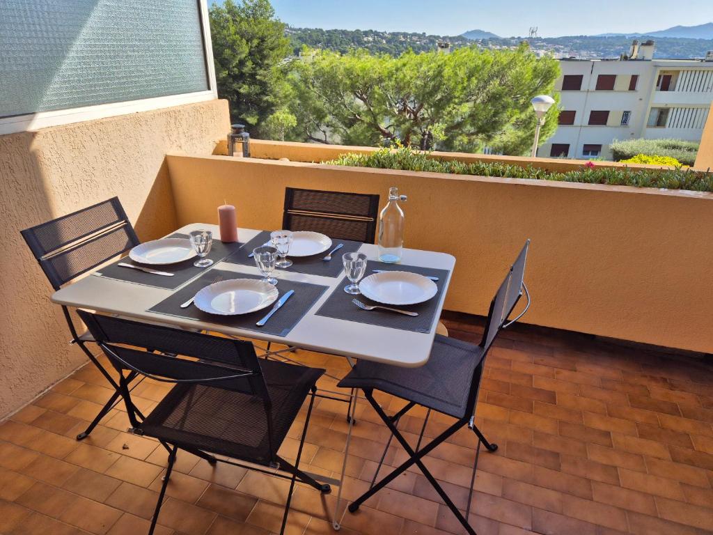 un tavolo e 4 sedie su un balcone con tavolo e sedie. di T2 vue mer dans résidence calme / T2 sea view in a quiet residence a Bandol