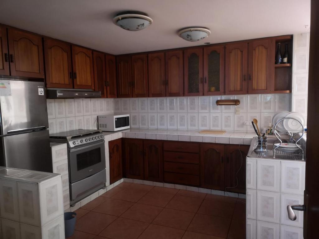 une cuisine avec des armoires en bois et des appareils en acier inoxydable dans l'établissement La Casa Junto Al Rio, à Arequipa