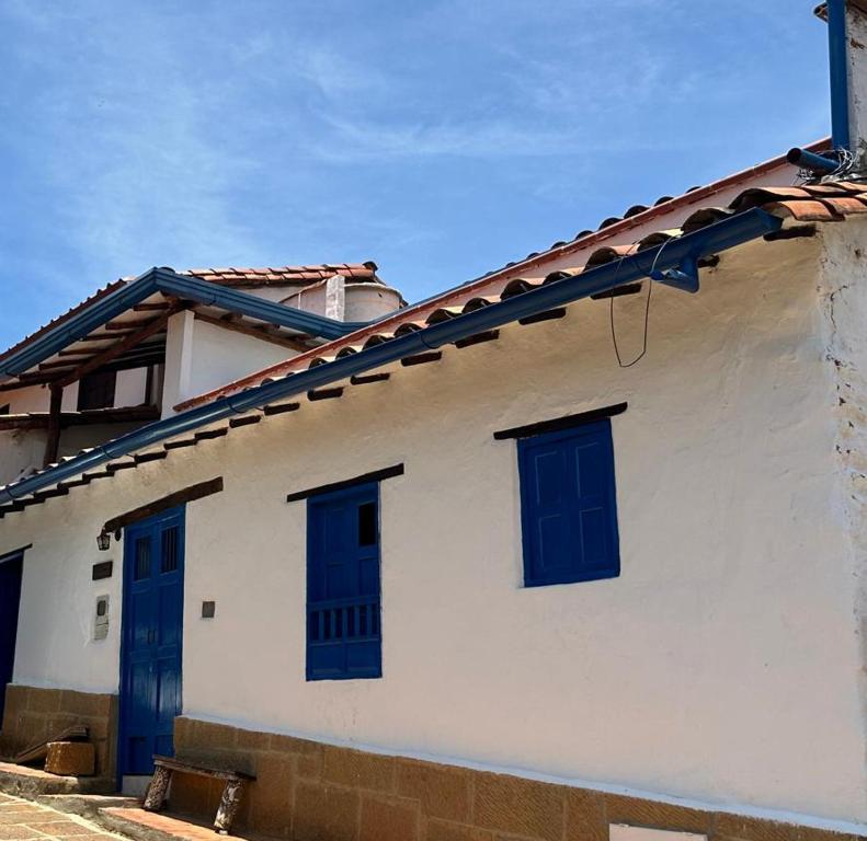 een wit huis met blauwe ramen en een dak bij Apartamento Ines María in Barichara