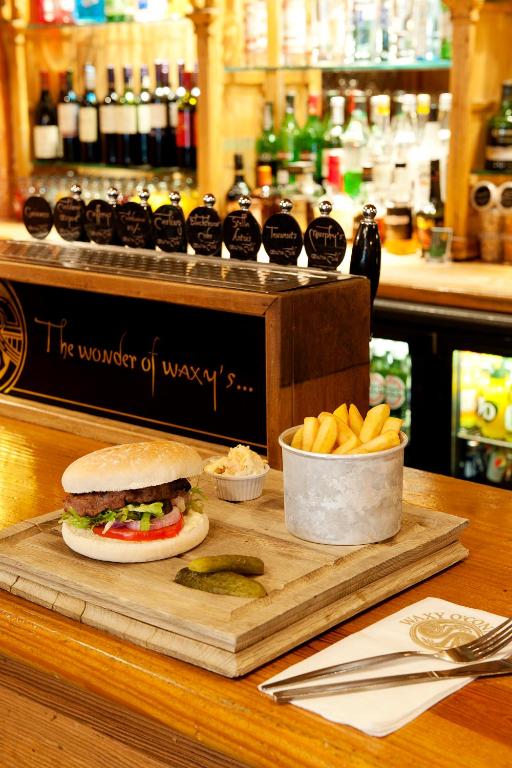 a sandwich and french fries on a wooden cutting board at Carlton George Hotel in Glasgow