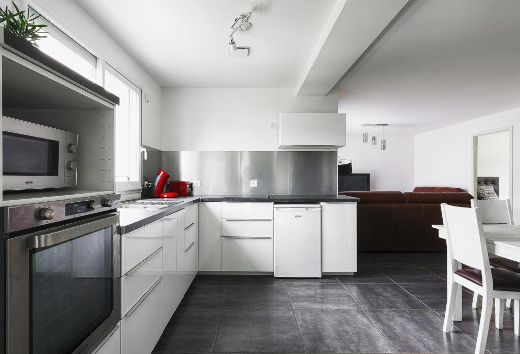 a kitchen with white cabinets and a microwave at Appartement de 70 m2 dans maison comptenporaine in Charnècles