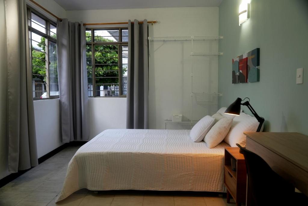 a bedroom with a bed with white sheets and a window at Ideal para trabajar y descansar in Cali