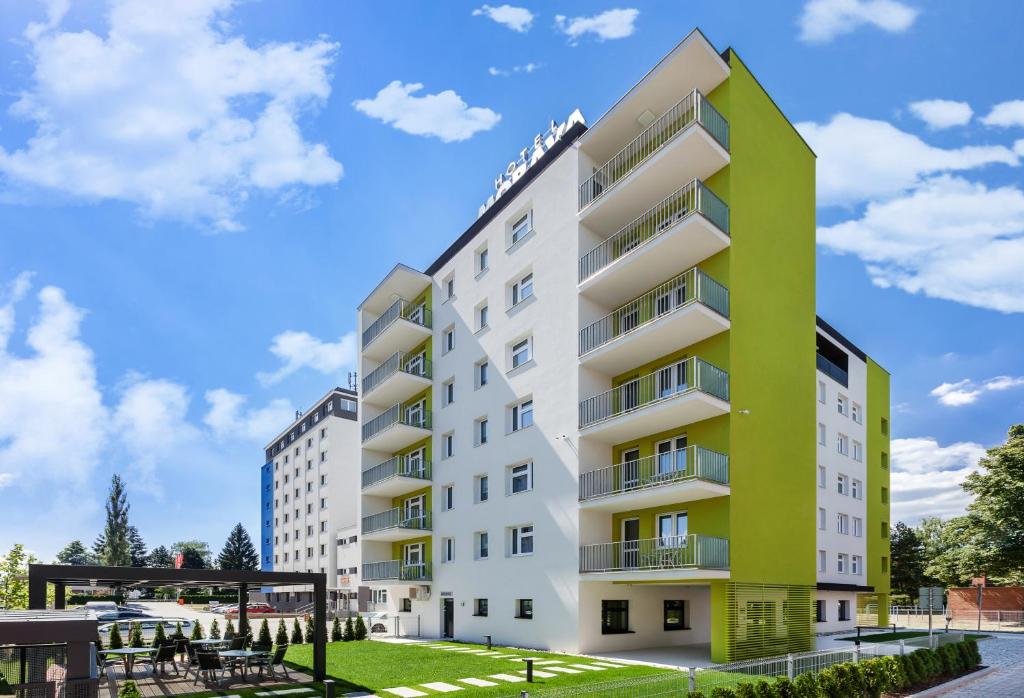 オトロコヴィツェにあるHotel Moravaの緑と白の外観のアパートメントビル
