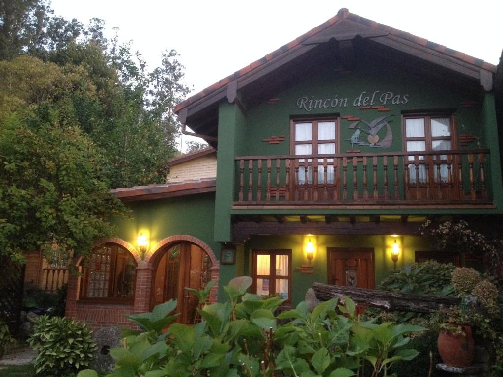 una casa verde con un reloj a un lado. en Posada Rincón del Pas, en Puente Viesgo