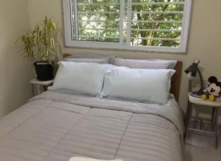 une chambre avec un lit avec des draps blancs et une fenêtre dans l'établissement Casa ao lado Pedreira Paulo Leminski confortável 15 min centro da cidade e centro histórico pontos turísticos shows eventos fácil acesso com estacionamento, à Curitiba