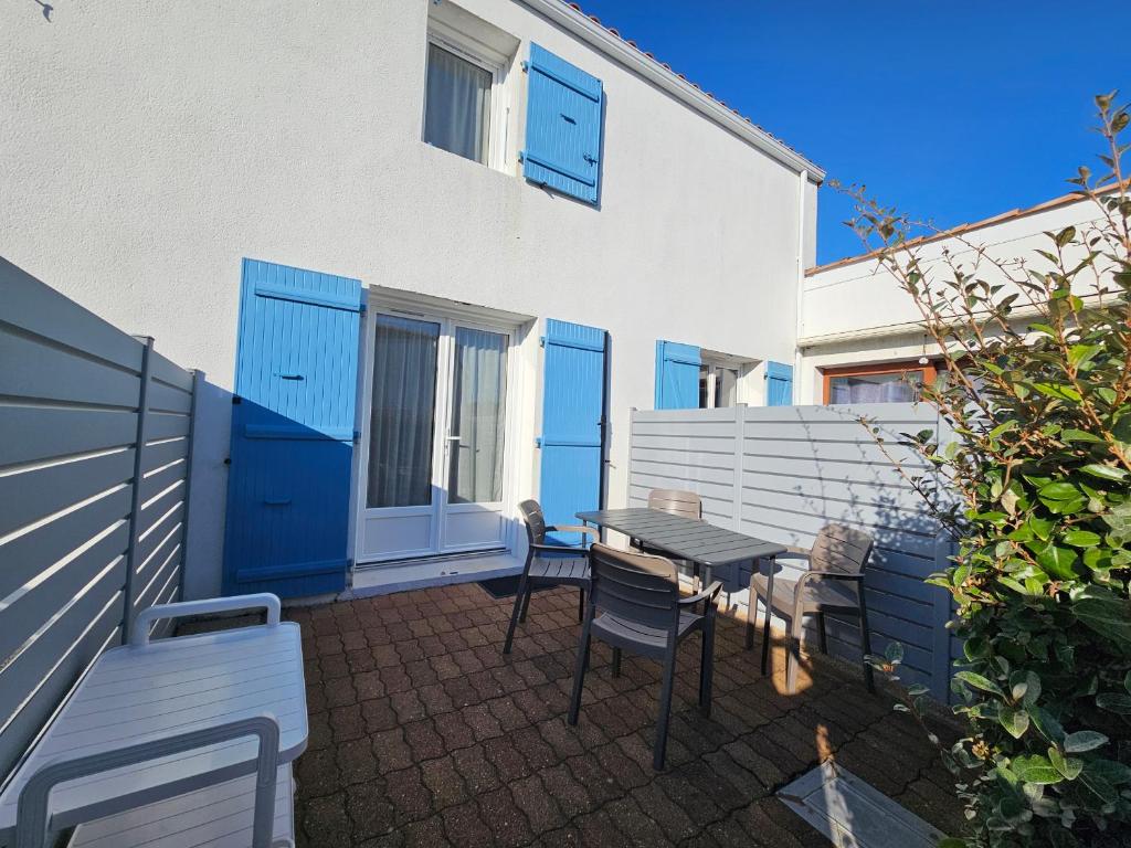 a patio with a table and chairs in front of a building at Maisonette Ensoleillée Proche Plage à La Faute-sur-Mer – 4 Pers, Animaux Sur Demande - FR-1-476-21 in La Faute-sur-Mer