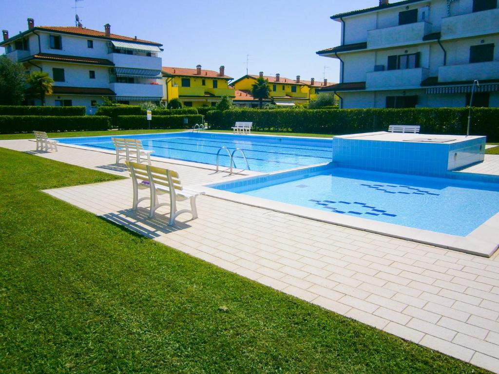 a swimming pool with two chairs next to a building at Villaggio Laguna - Agenzia Cocal in Caorle