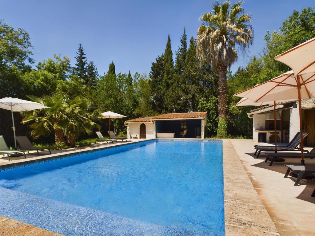 - une piscine avec des chaises et des parasols à côté d'une maison dans l'établissement Mas rénové à Mouriès avec piscine, 6 chambres, terrasses et pool houses, en pleine nature provençale. - FR-1-599-90, à Mouriès