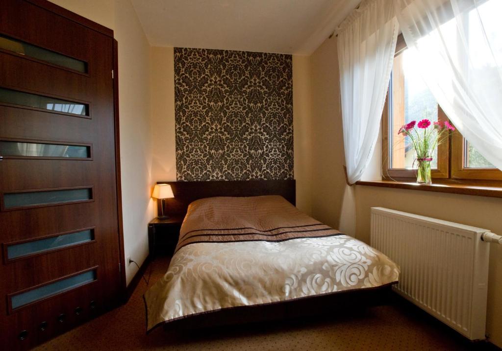 a small bedroom with a bed and a window at Aldian Pokoje Gościnne in Szczyrk