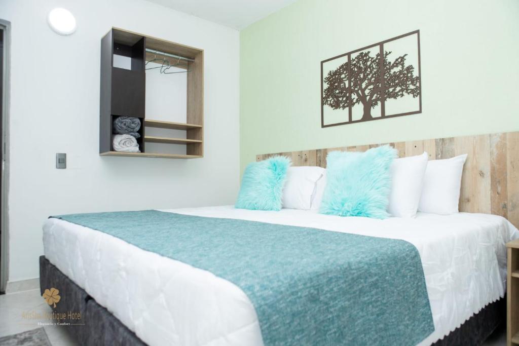 a bedroom with a large bed with blue pillows at ArisSha Boutique Hotel in Cali