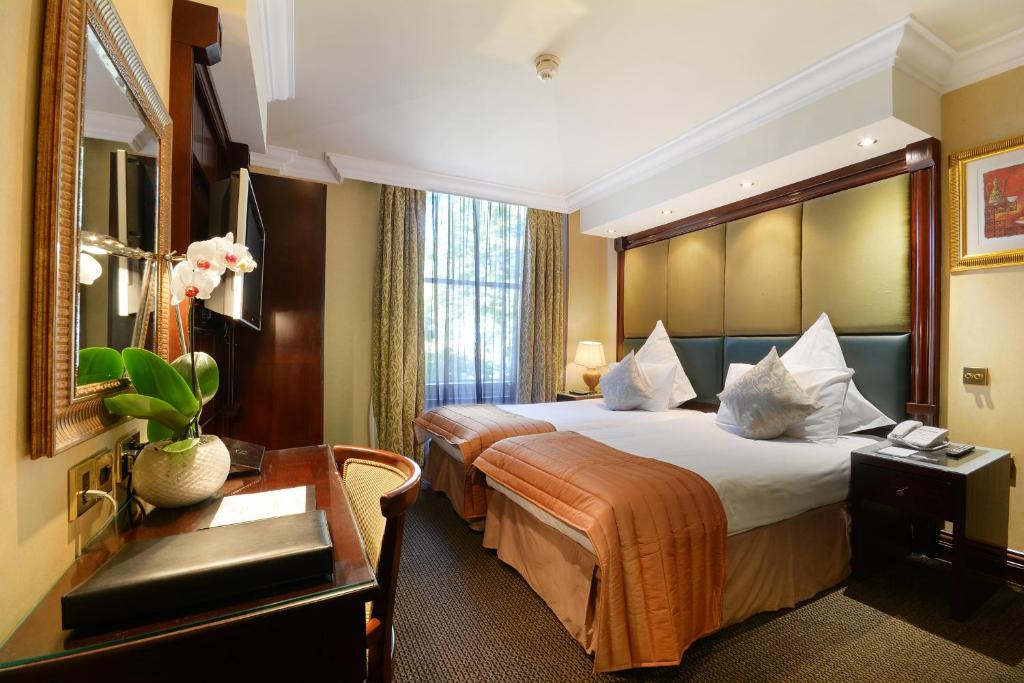 ロンドンにあるザ プレミア ノッティングヒルの大きなベッドとデスクが備わるホテルルームです。