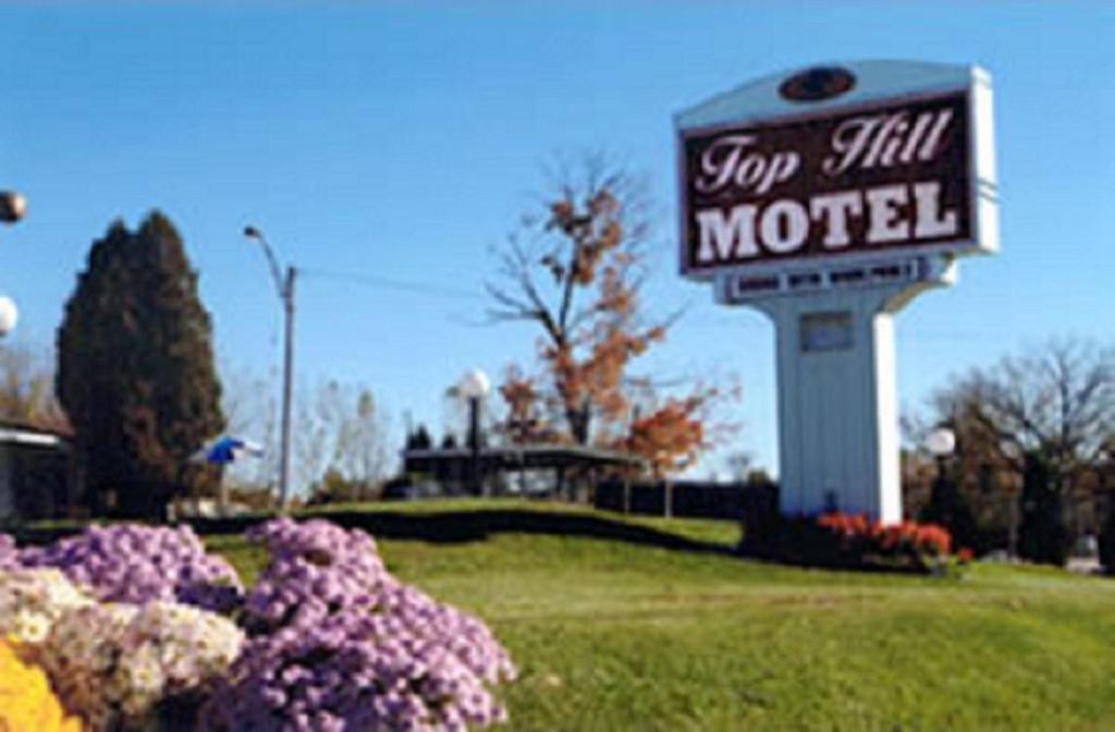 een bord voor een stop nog steeds motel naast enkele bloemen bij Top Hill Motel in Saratoga Springs