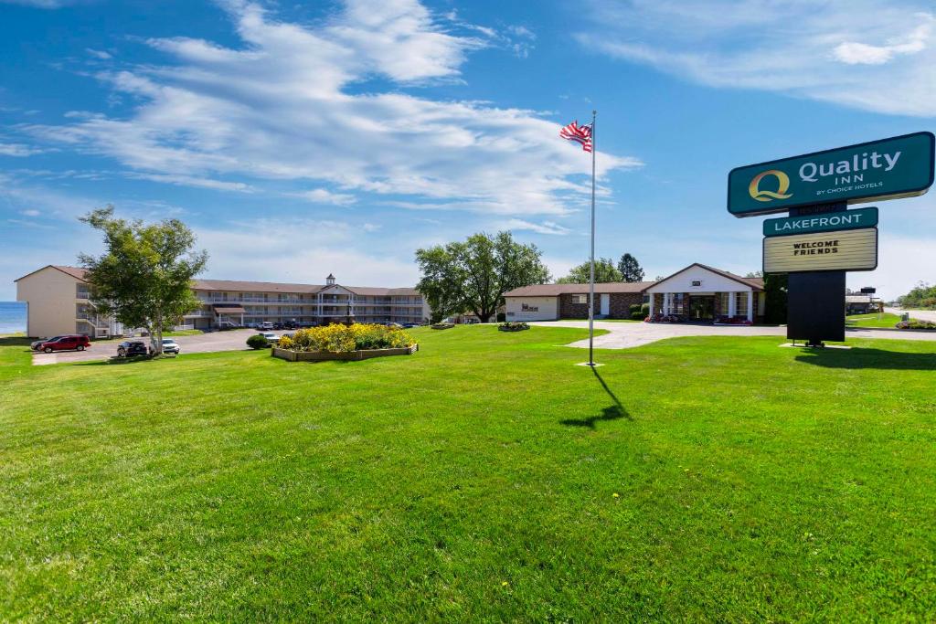 a building with a sign and a flag in a field at Quality Inn Lakefront in Saint Ignace