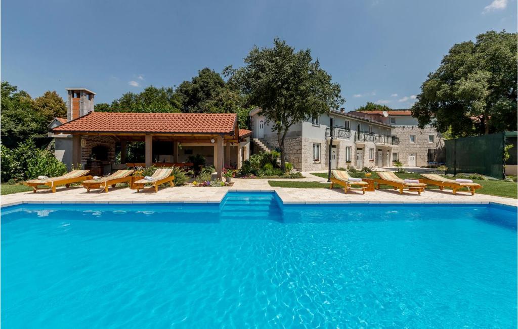 a large swimming pool with chairs and a building at Five-Bedroom Holiday Home In Vinjani Donji in Bilopavlovići